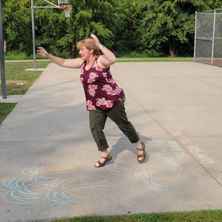 Blond-haired woman landing from a jump on a chalk-drawn palm tree.