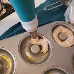 Donut batter being piped in to a pan.