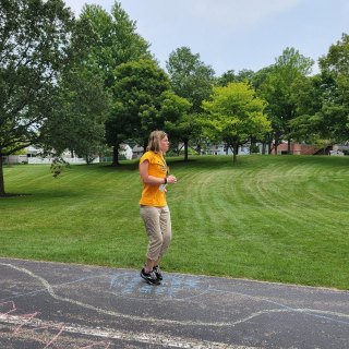 Woman with brown hair jumping on sidewalk