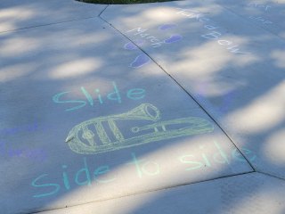 picture of slide trombone drawn in chalk on a sidewalk with the words slide side to side