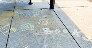 White chalk on sidewalk of the word books with pictures of books.